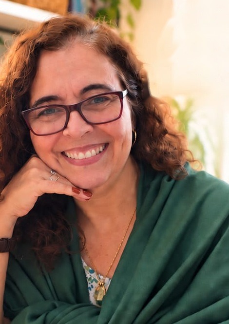 Ana Paula Vilhena, arquiteta e personal organizer, sorrindo com um xale verde